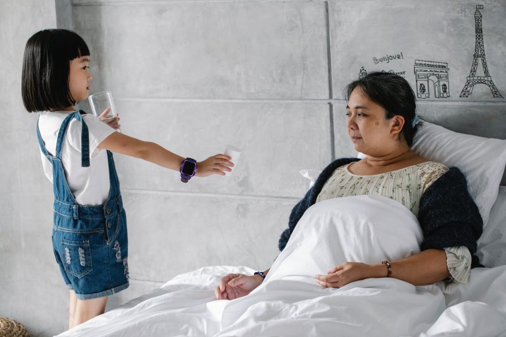 cute ethnic child taking care of ill grandmother resting in bed